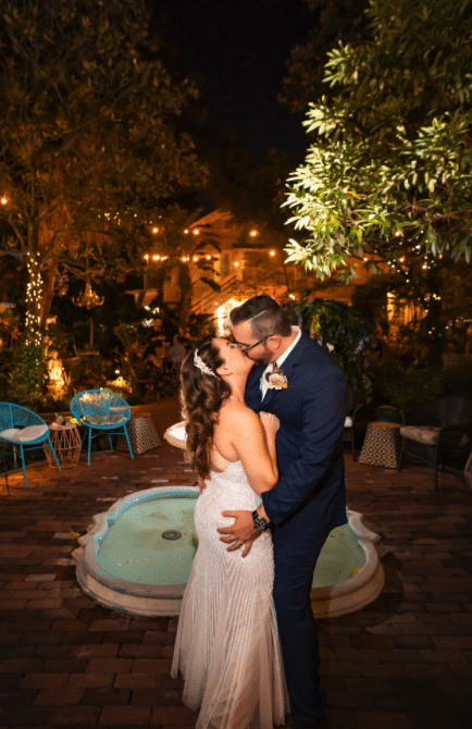bride and groom kissing on patio in front of fountain at night